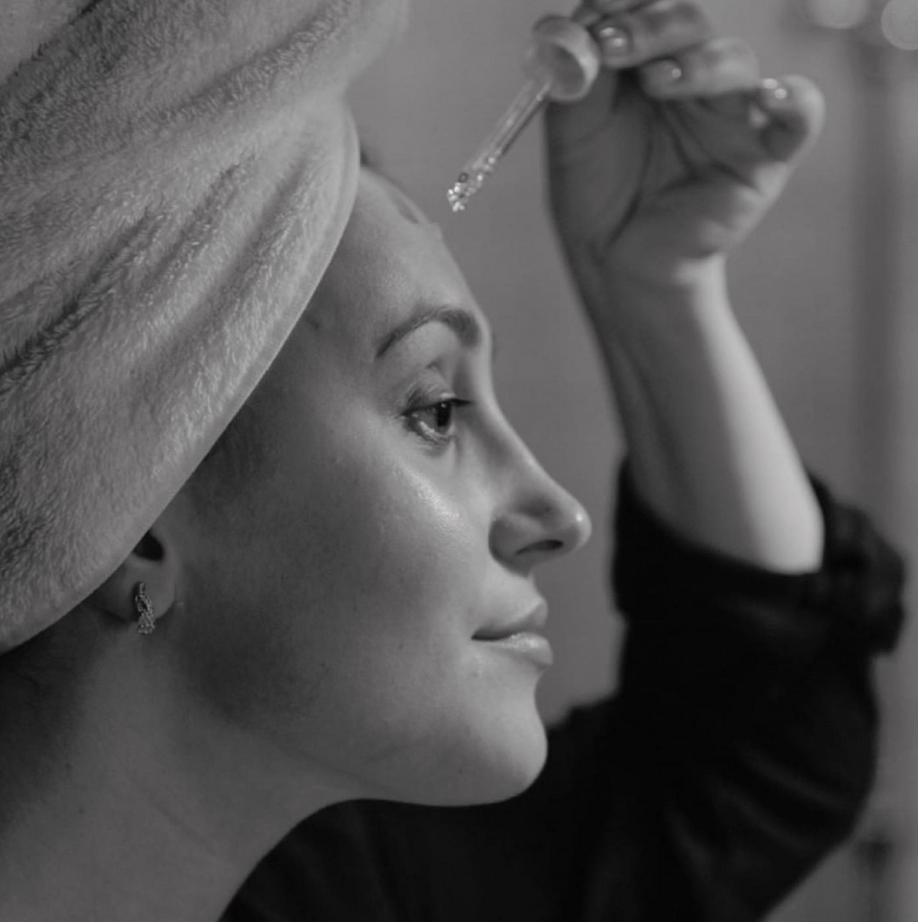 Femme dans salle de bain qui met de l'huile de cacay sur le visage
