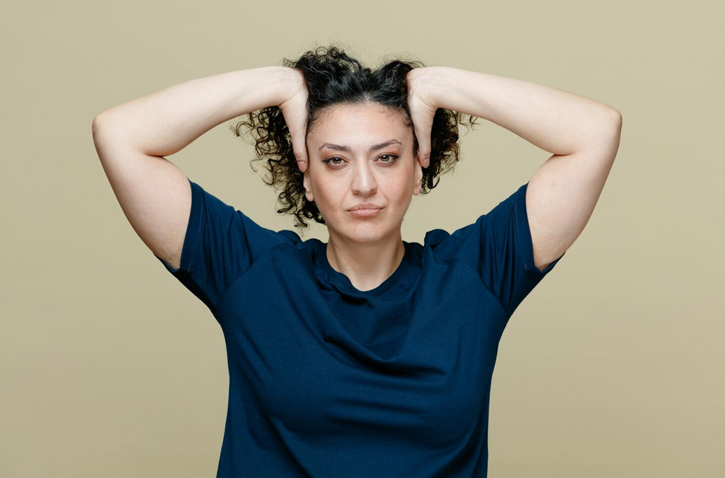 femme avec des cheveux gras de face se touche le crâne